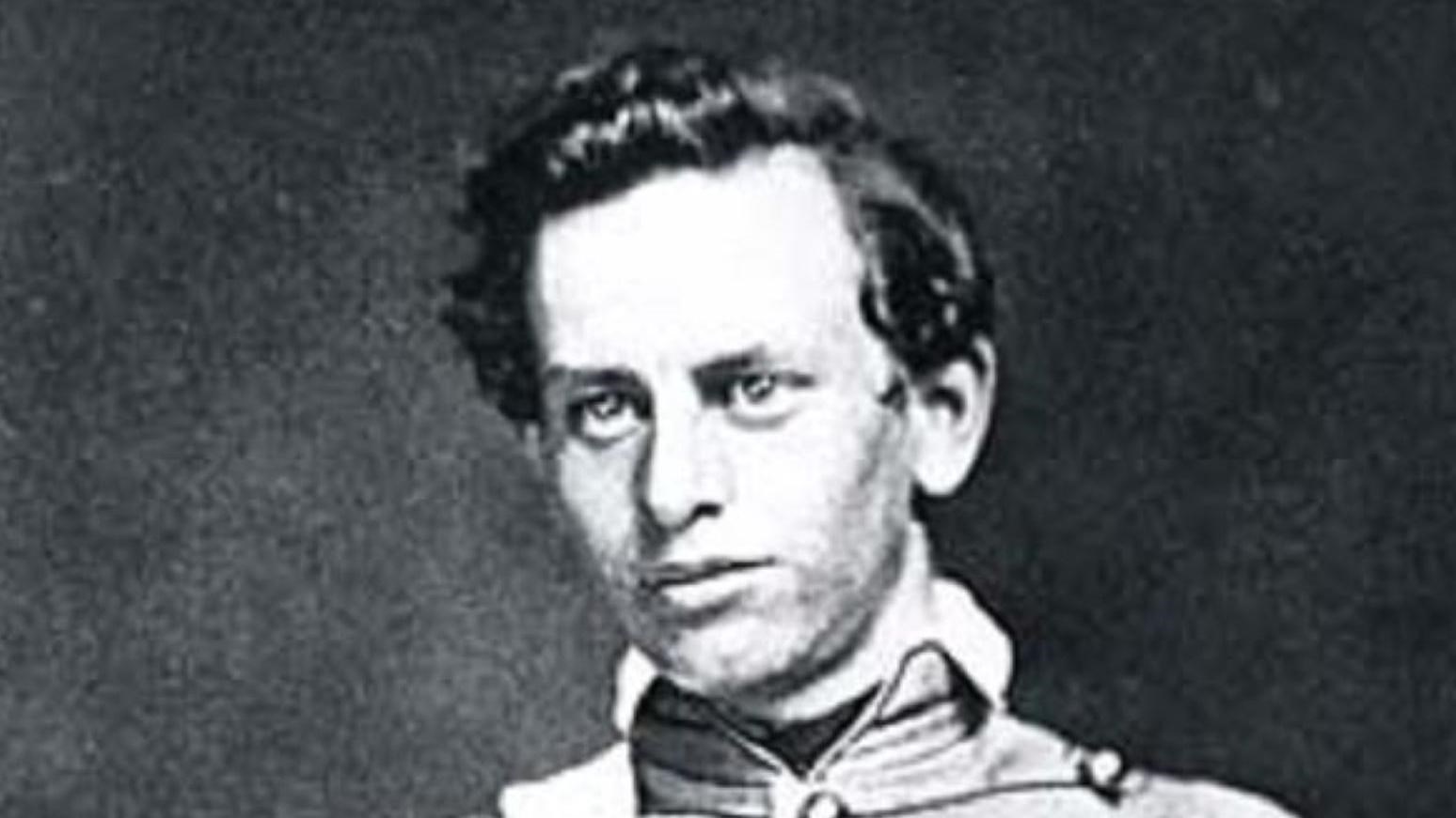 Black and white photograph of a man in military cadet uniform with a chest strap