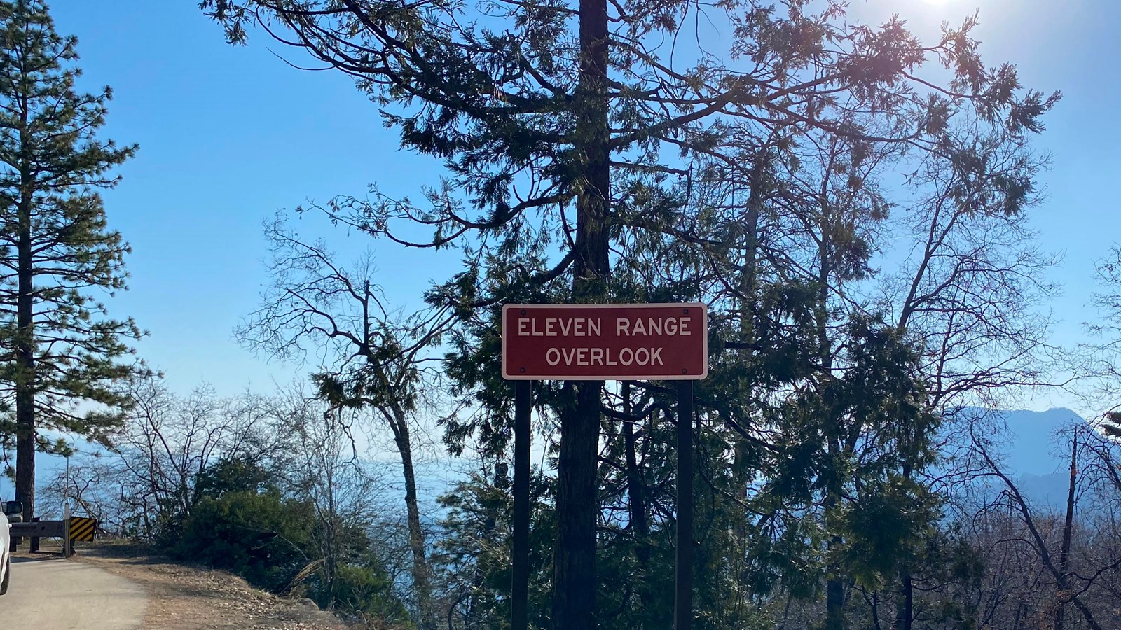 The brown sign for the Eleven Range Overlook with pine trees behind it. 