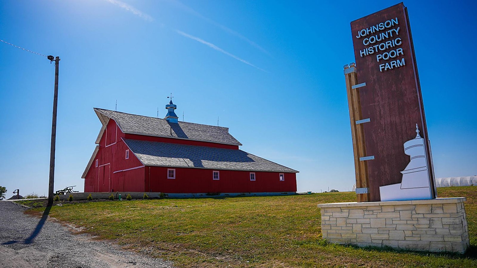 Large red barn with sign in foreground reading 