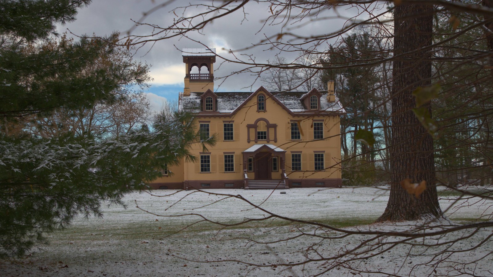 Photo of Van Buren\'s home draped in snow taken through tree branches.