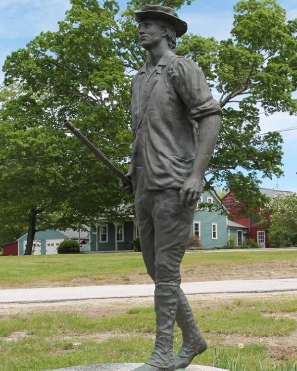 A statue of a young person in colonial attire carrying a musket and in mid-stride. 