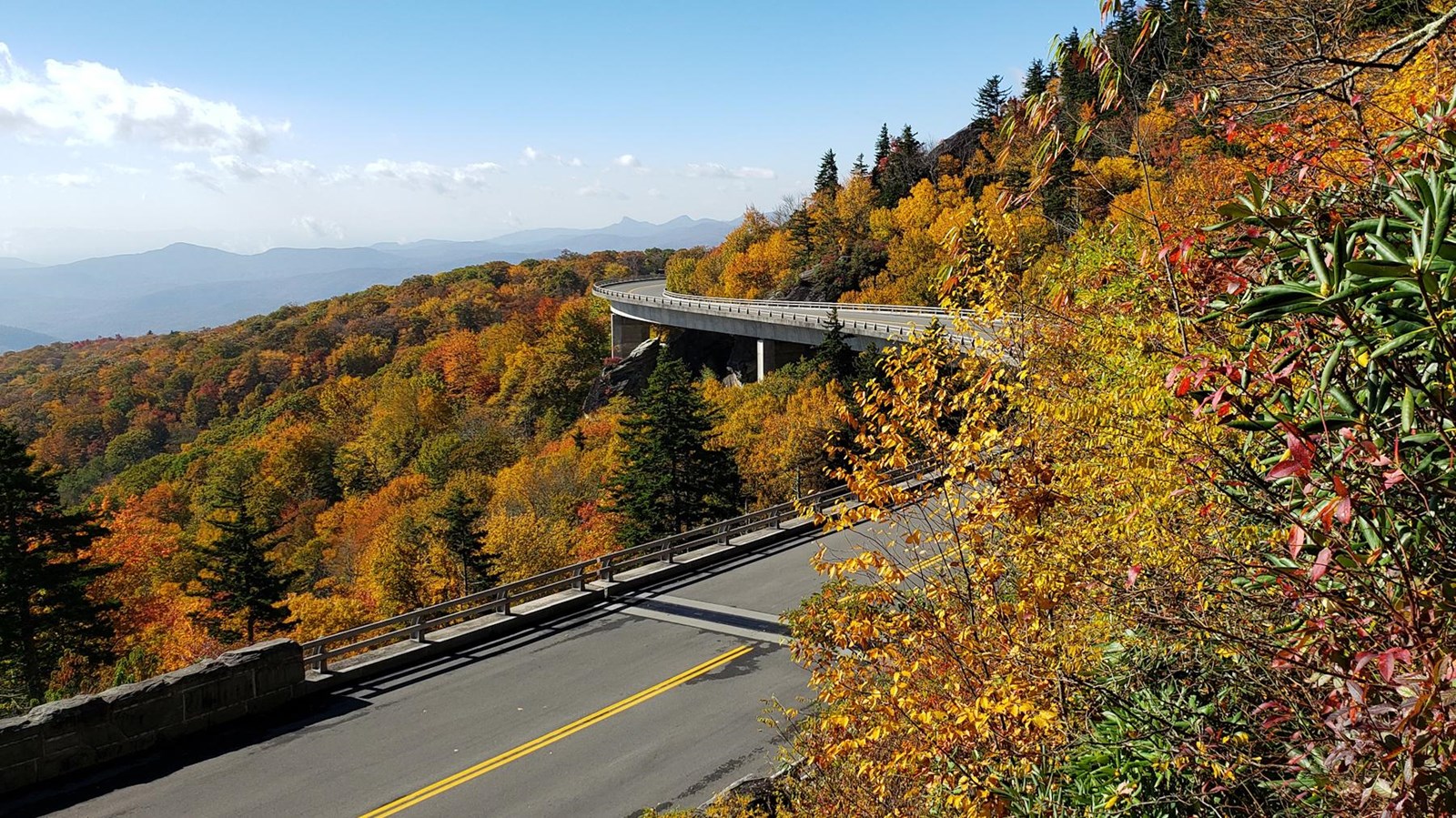 A roadway curves sinuously across a colorful fall landscape