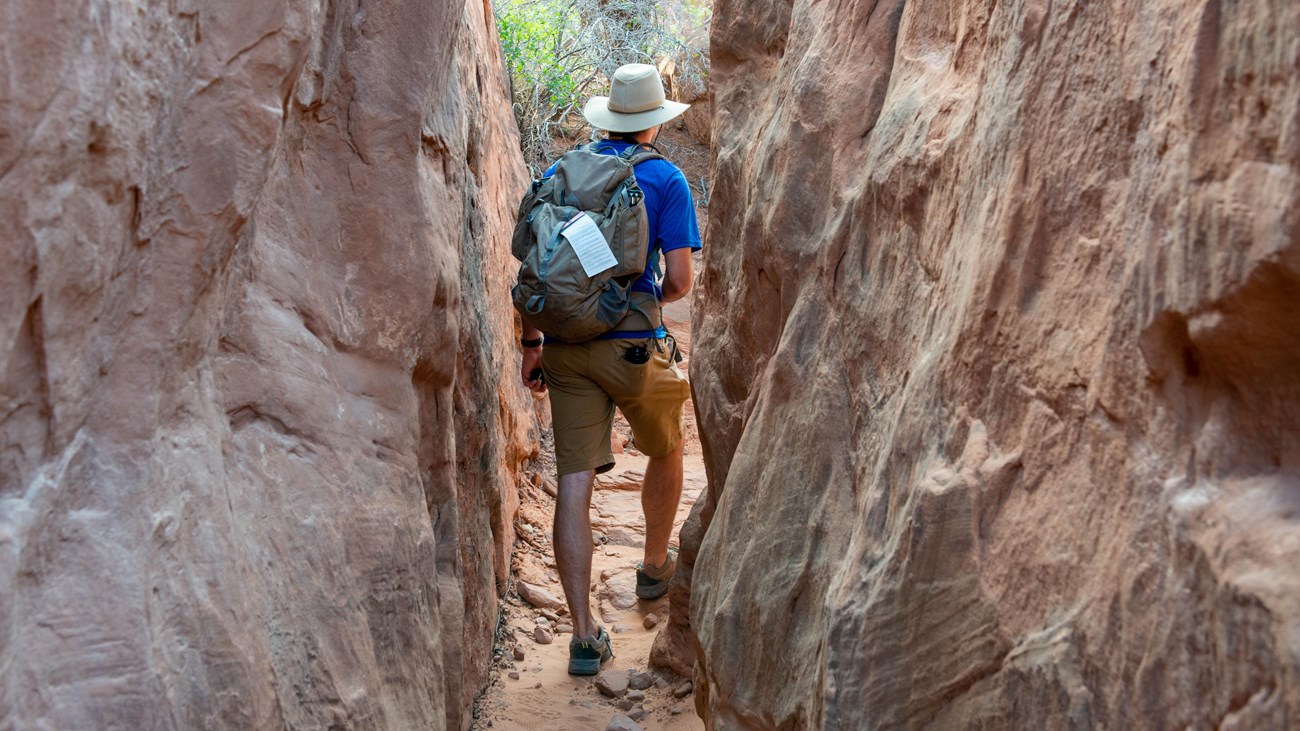 hiker with permit in narrow path between tall rock walls