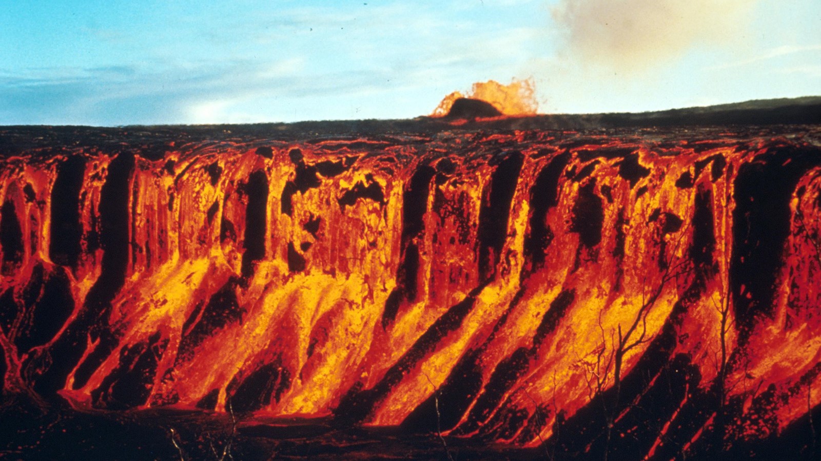 Molten lava cascading into a crater at night. 