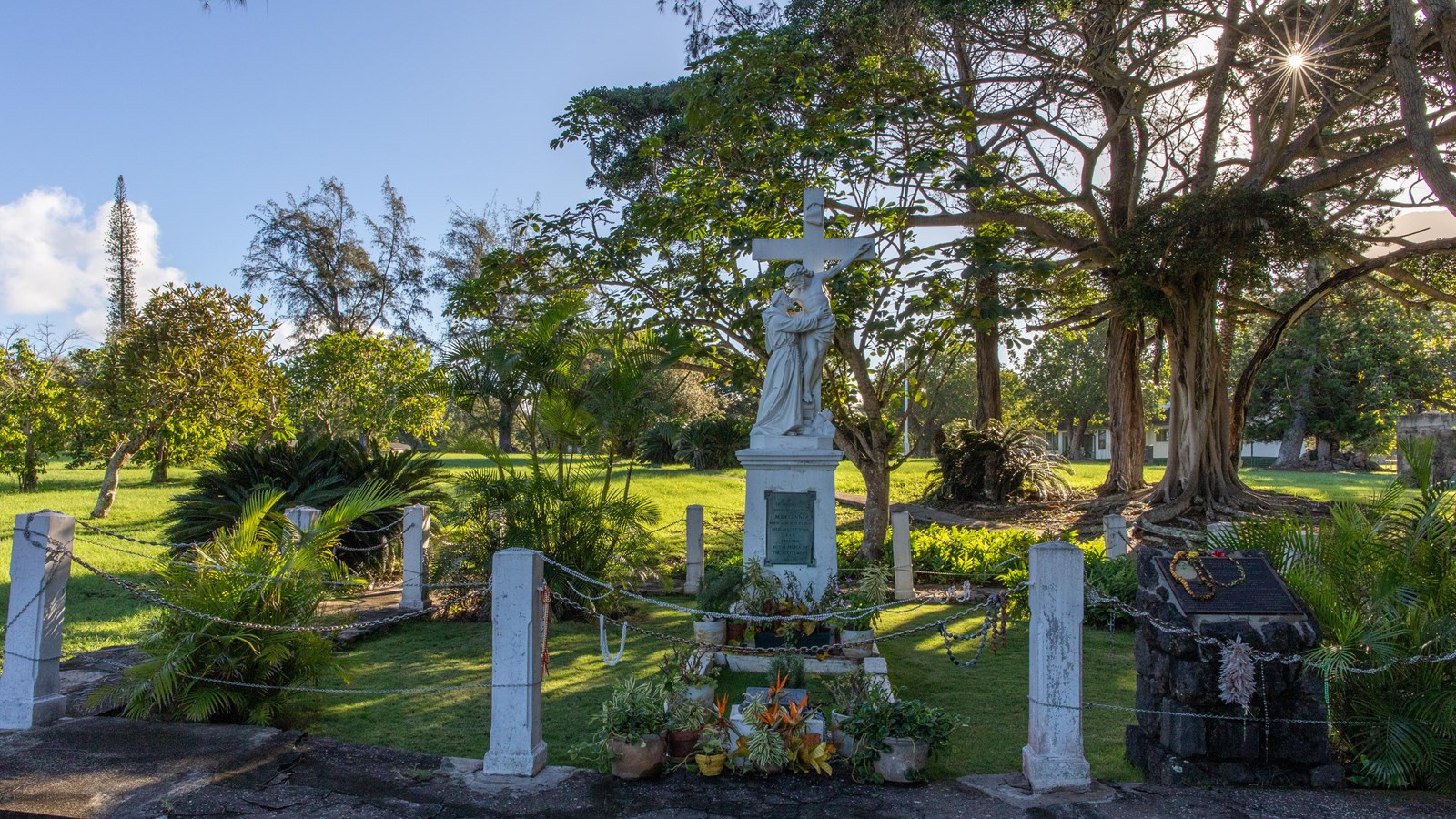 An ornate grave site with a statue and plants.