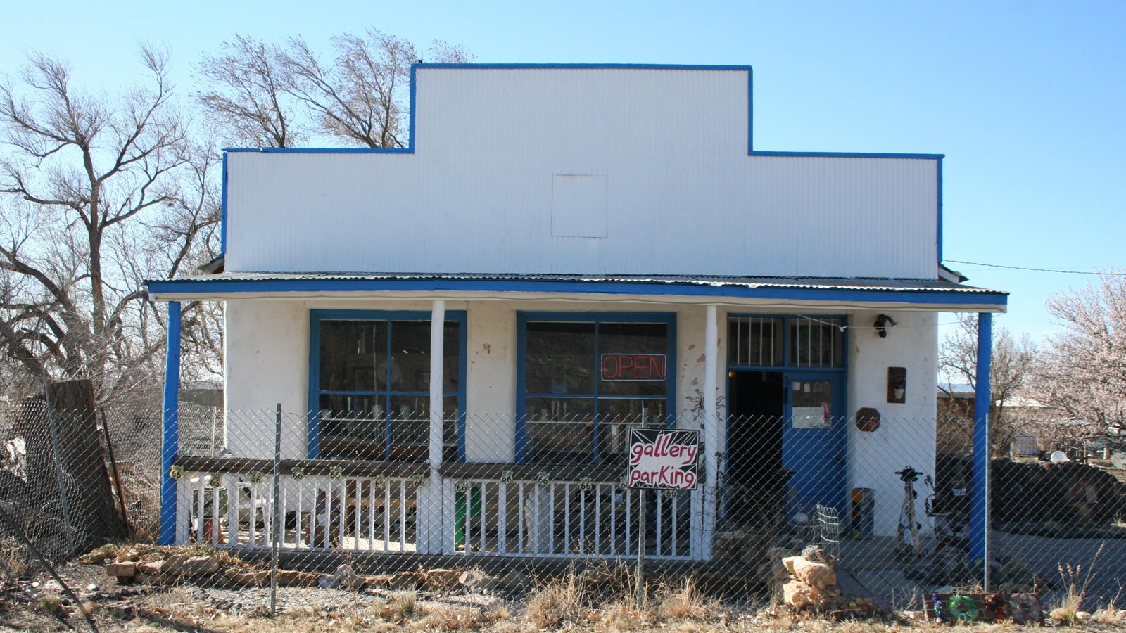 A small white adobe building, with blue trim and a covered front patio.