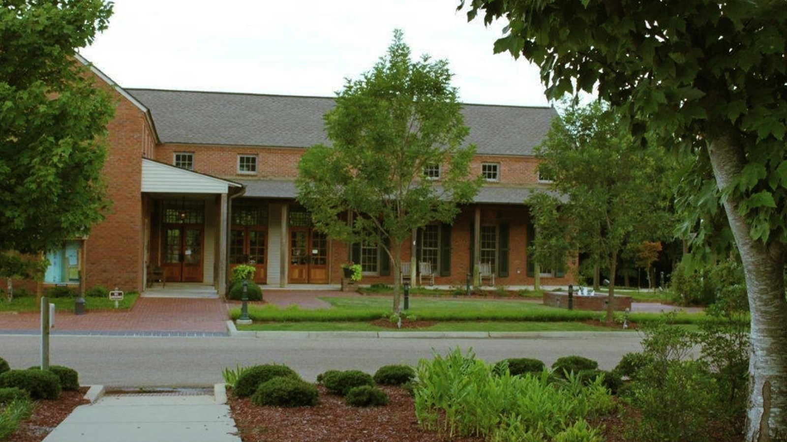 A brick building with pretty landscaping and a broad porch to visit.