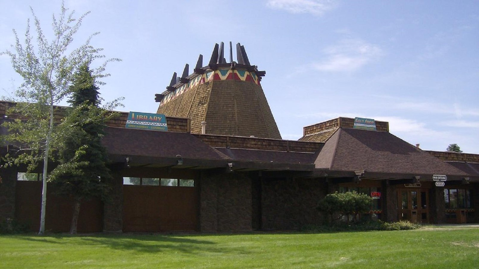 A large brown brick building with the roof of a recreated native building in it\'s center 