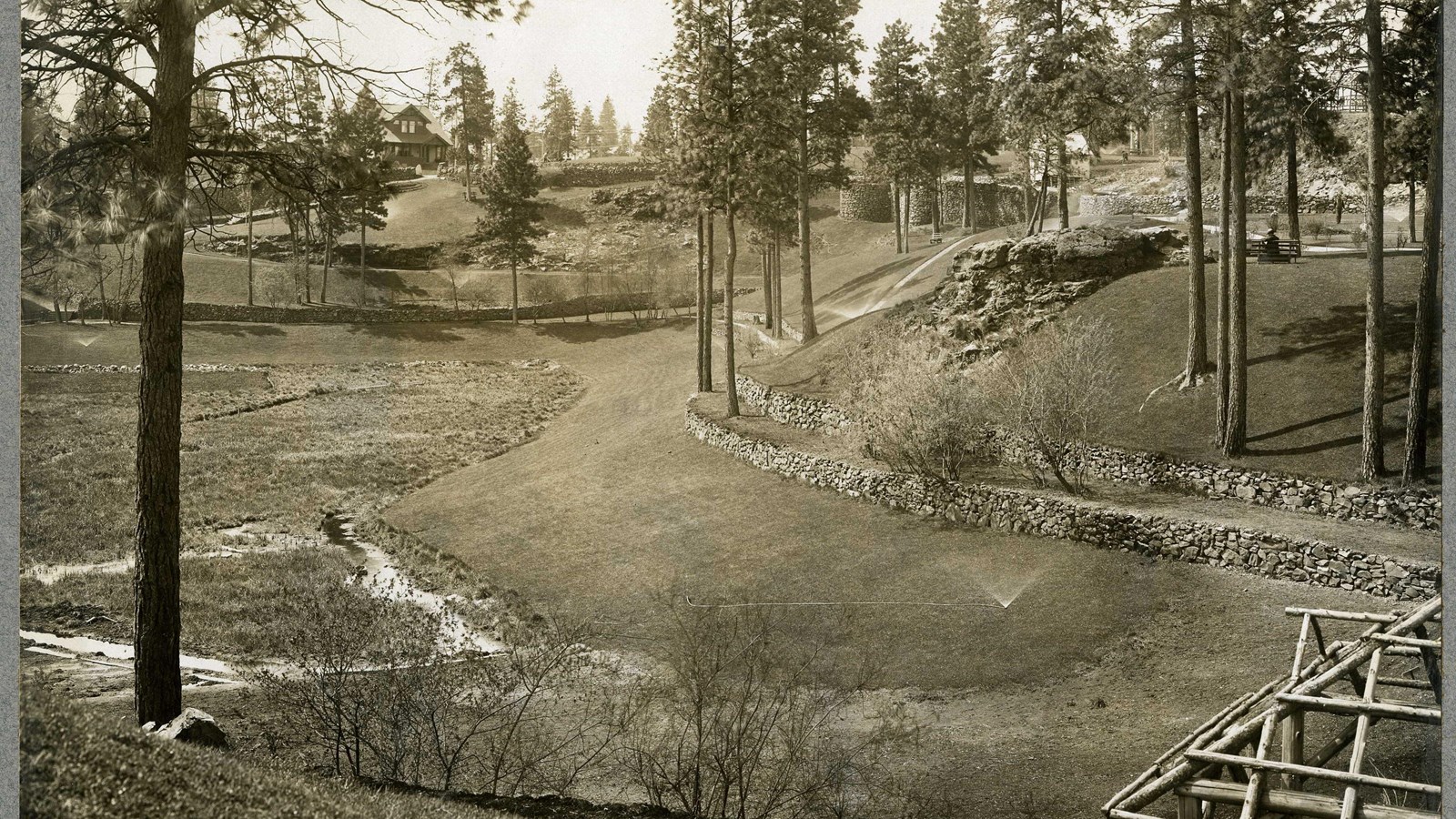 Black and white of hilly area with several rock ledges with trees along the ledges
