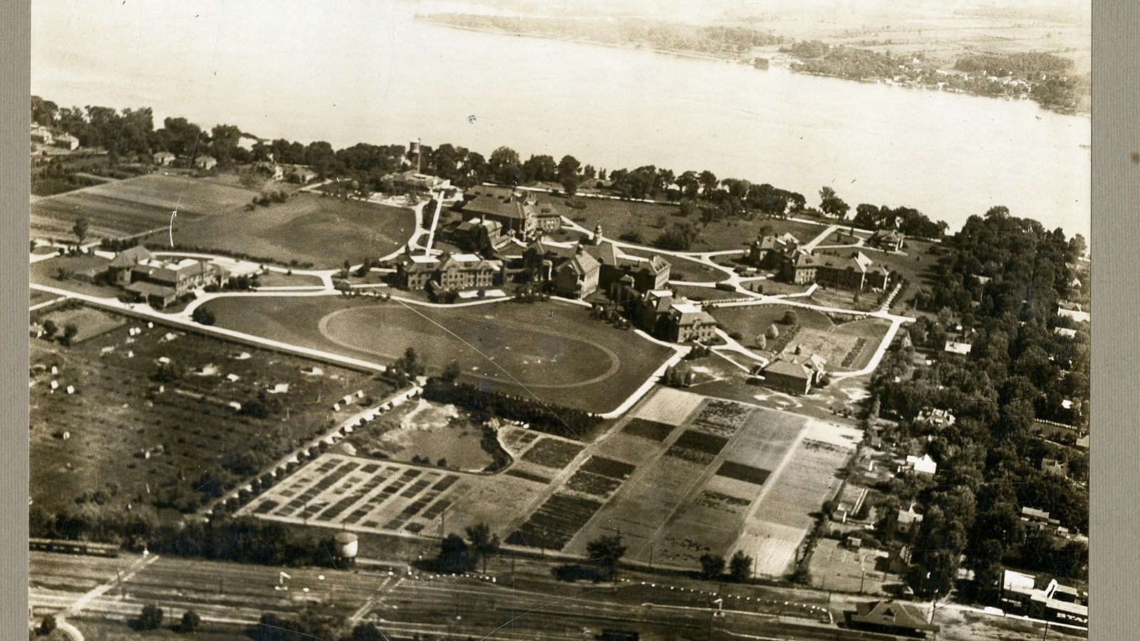 Black and white aerial of campus with lots of buildings and lots of paths, flat green space inside