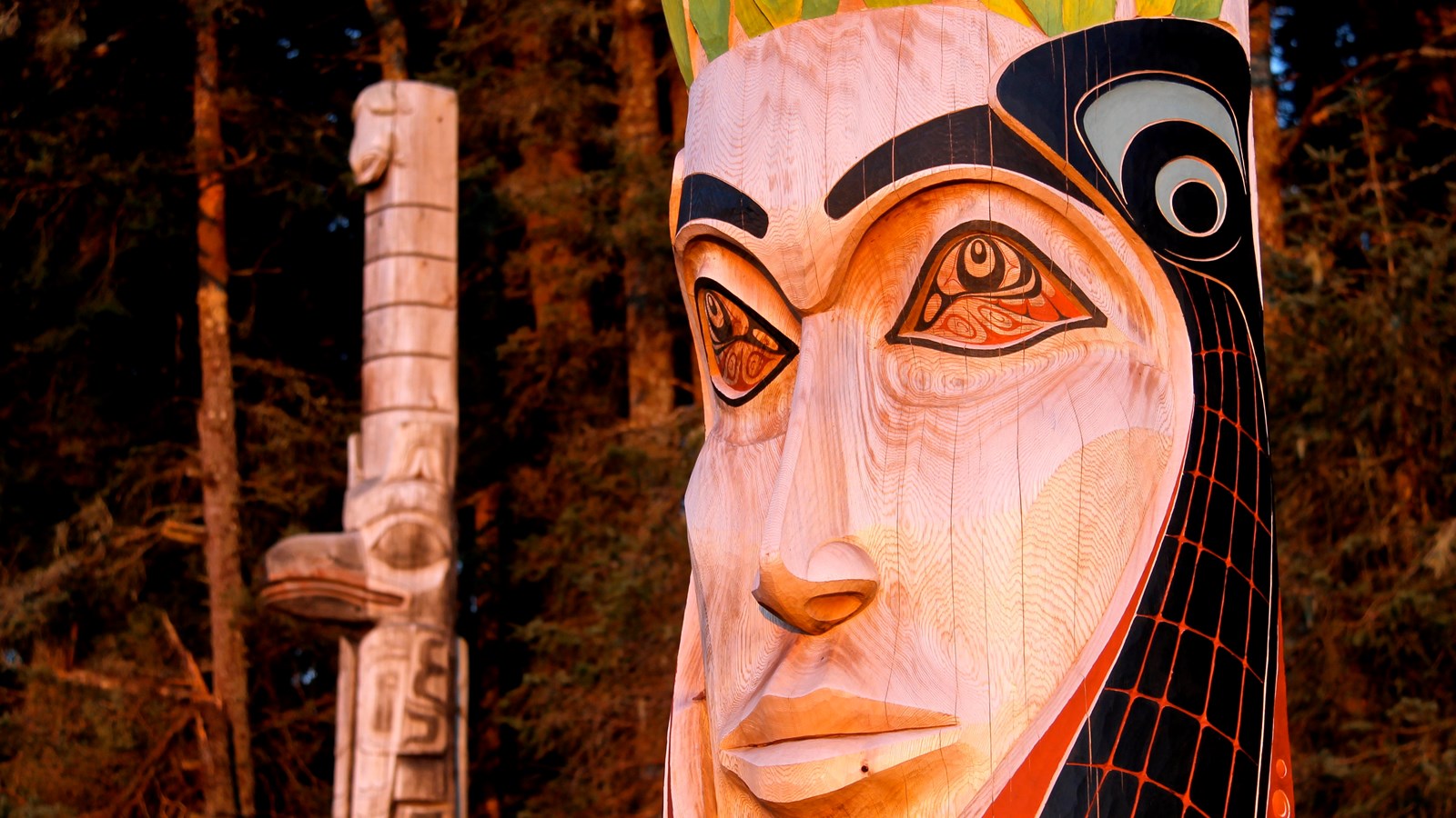 Two totem poles near a trail head