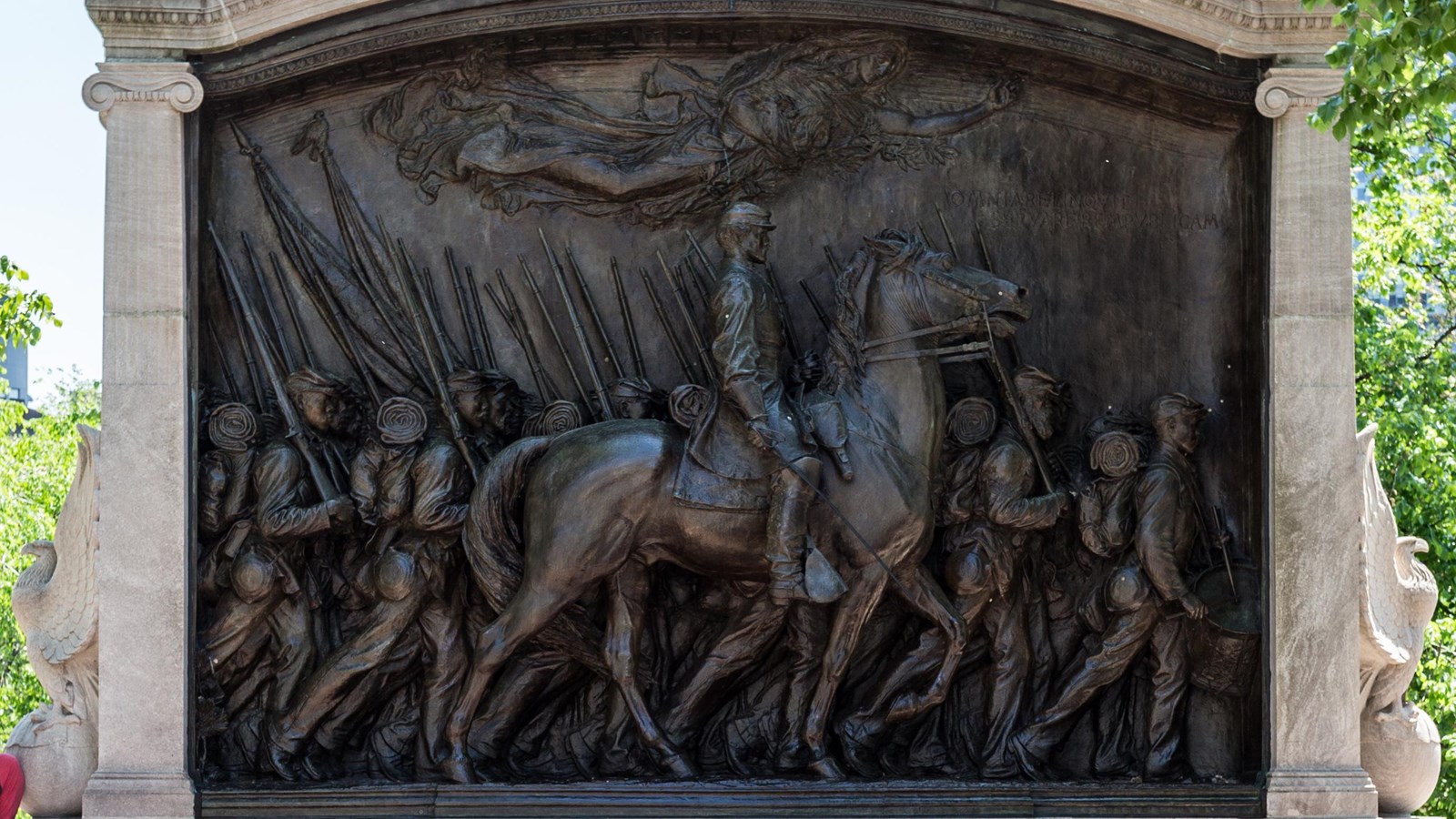 Monument of a man on a horse with multiple soldiers marching around him.