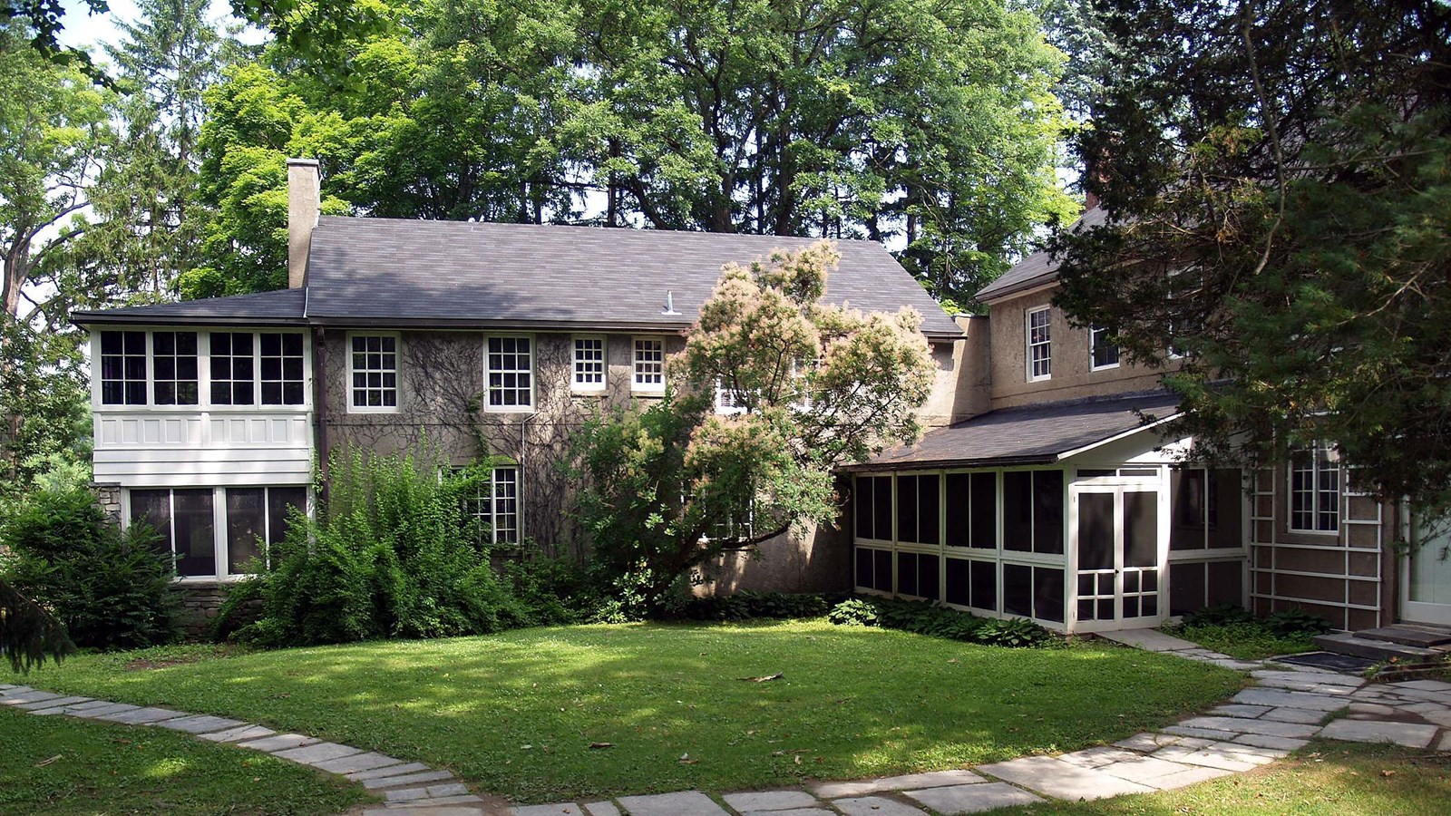 A two-story stucco cottage with screened porches.