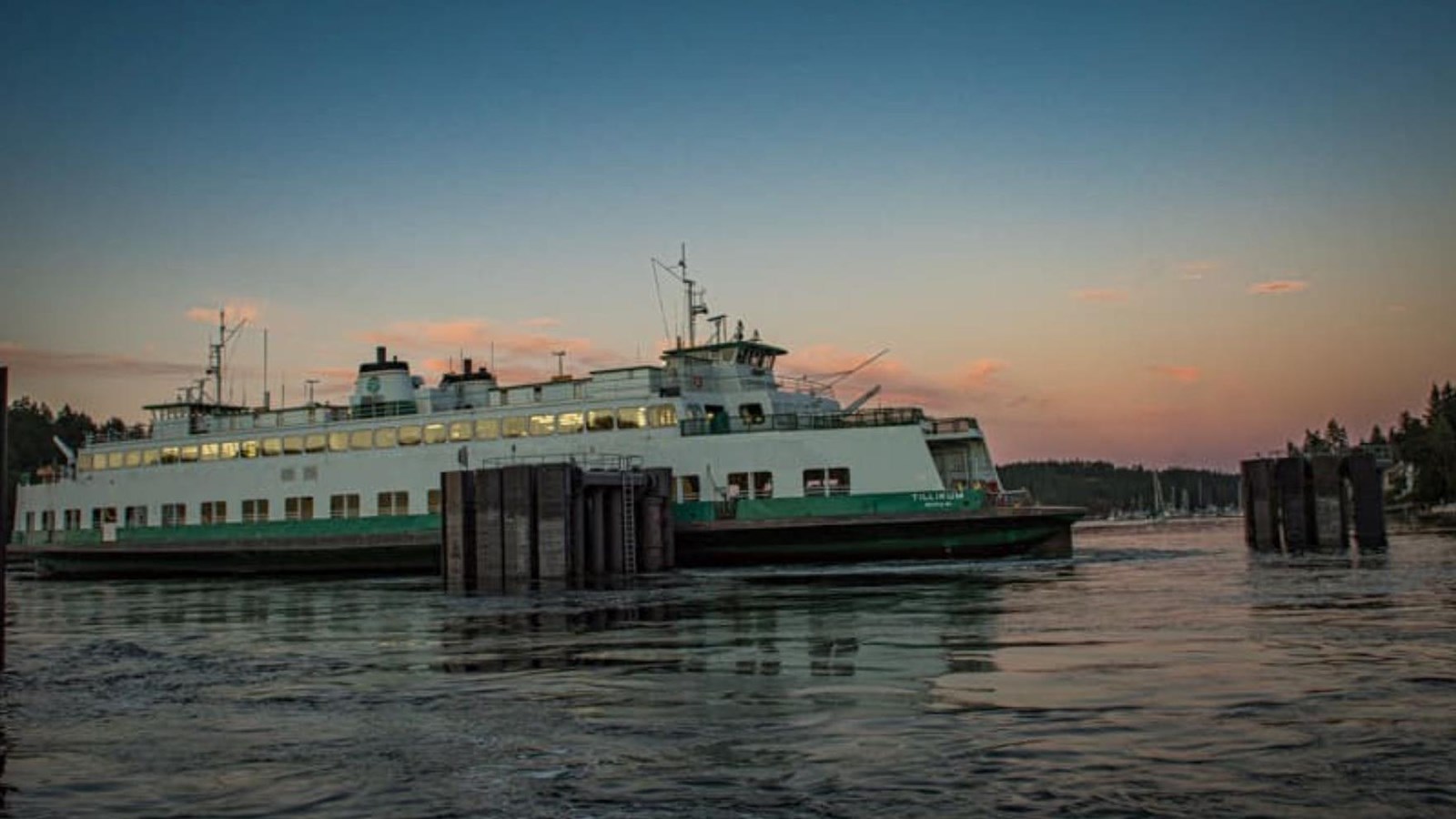 color photograph of a green and white ferry docking at sunset
