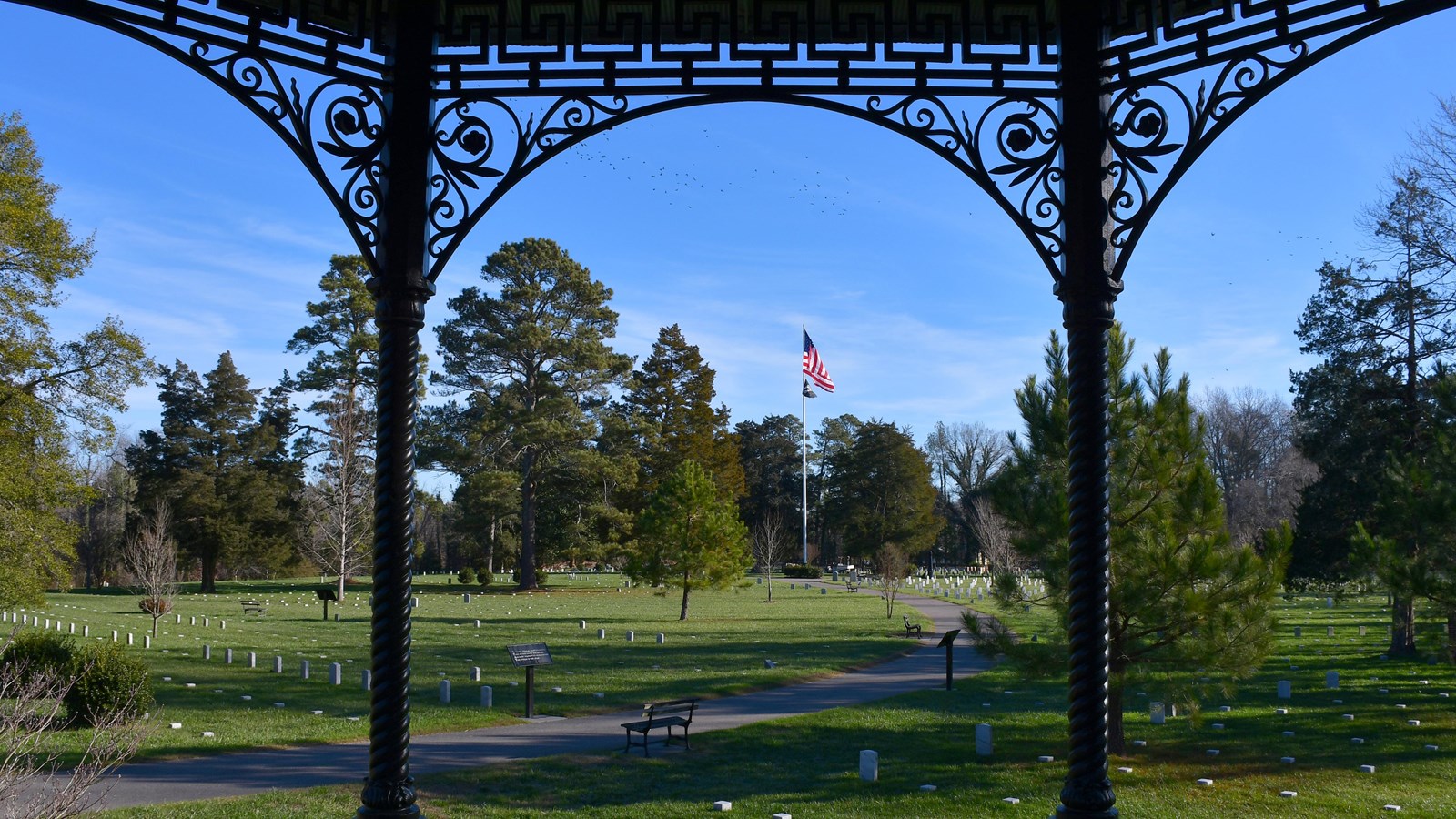 Rod-iron columns frame a view of thousands of white marble headstones.