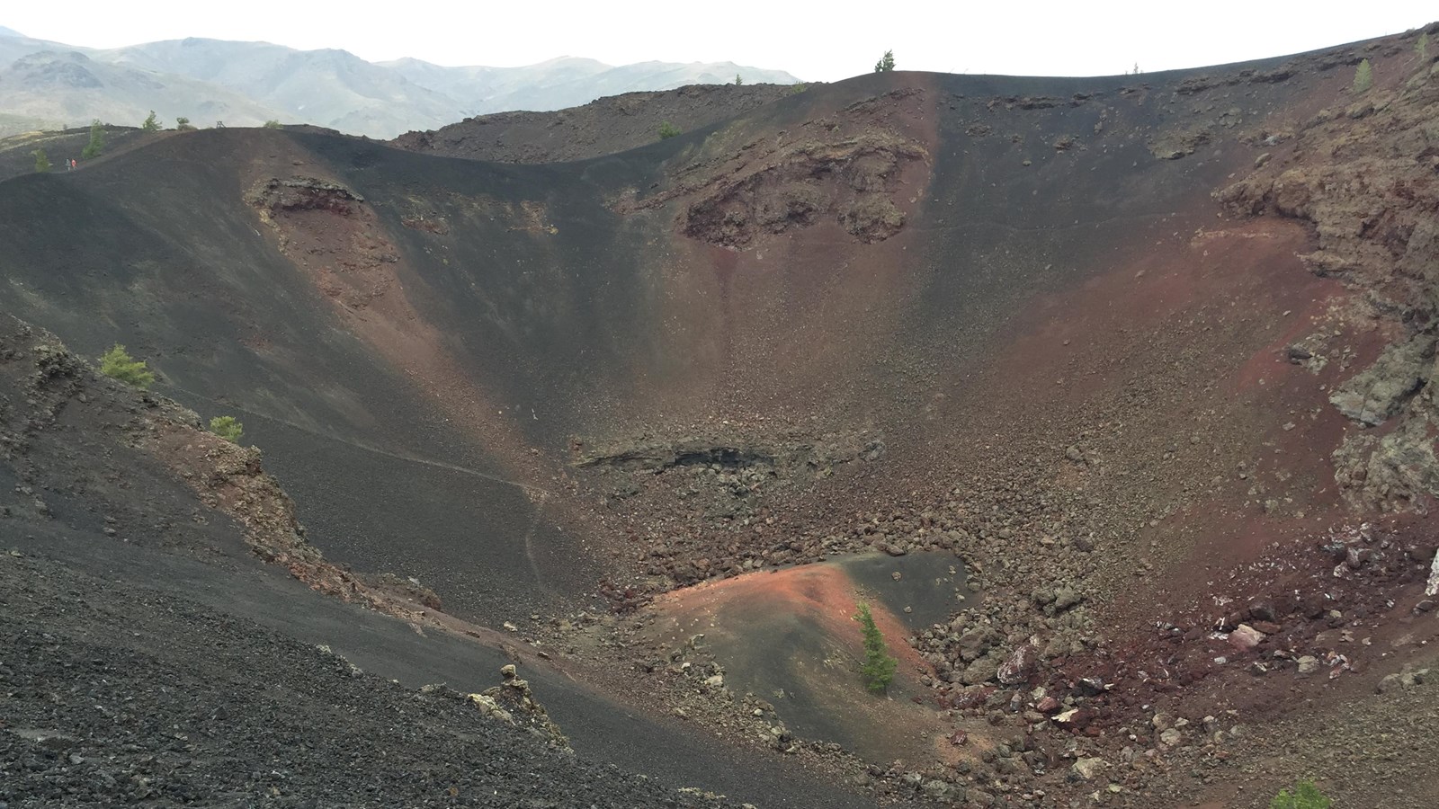 a large volcanic crater with black and reddish-brown stripes around the edges