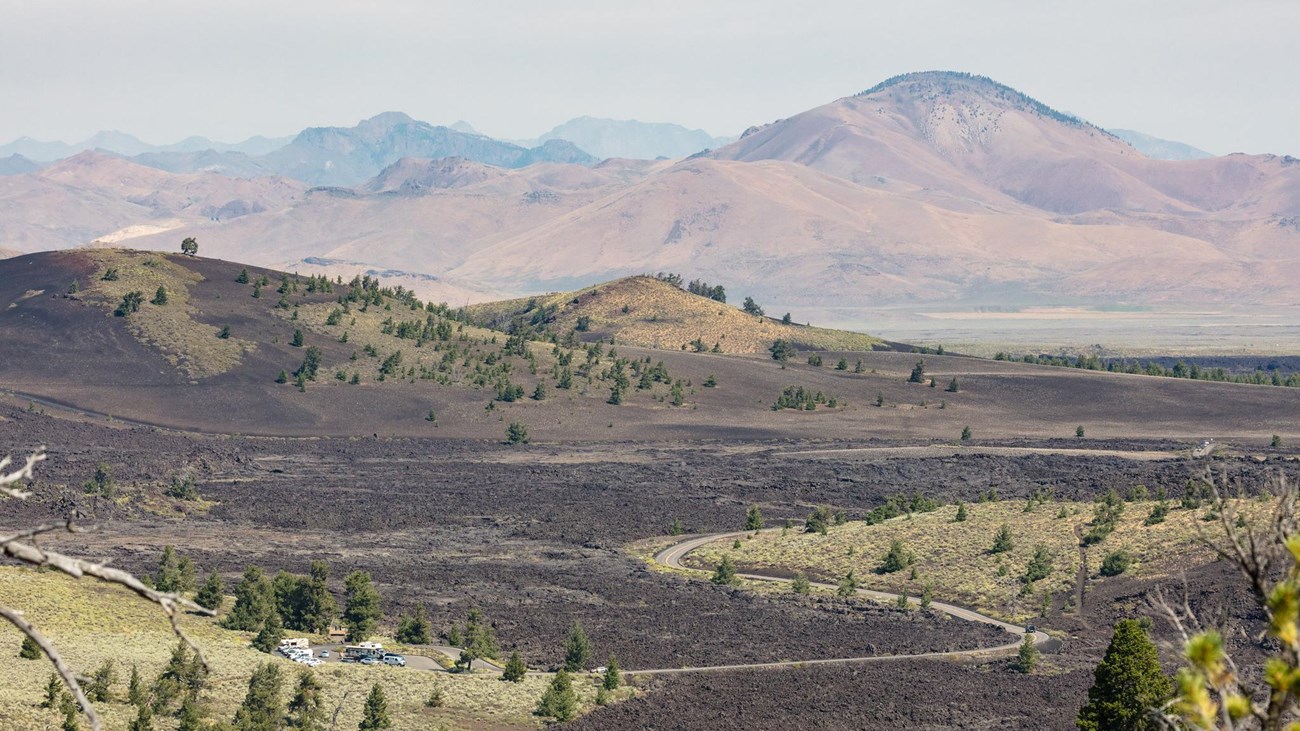 A narrow road winds through a volcanic landscape to a small parking area.