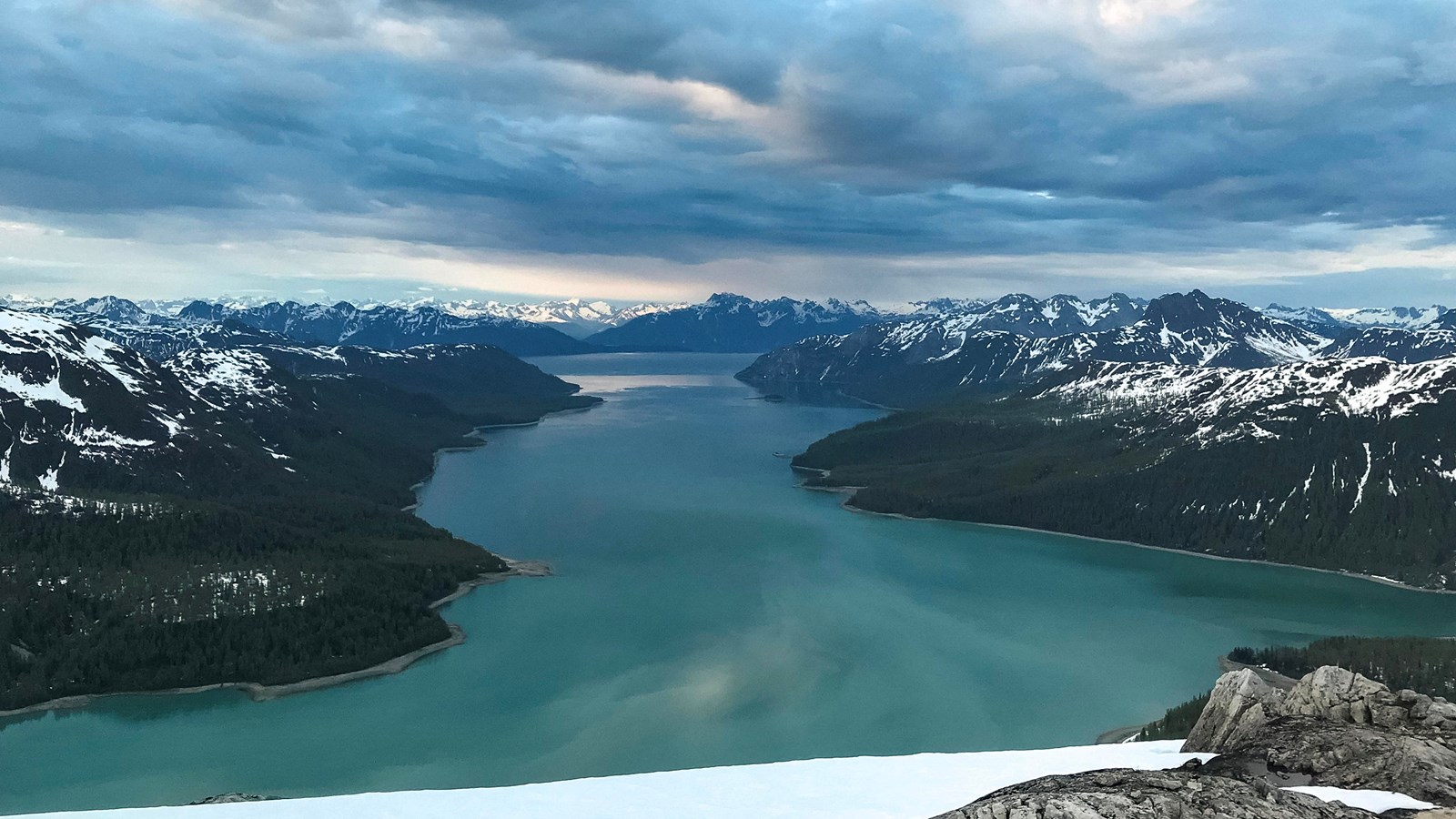 Tall mountains shrouded in clouds surround the branches and islands of Geikie Inlet.