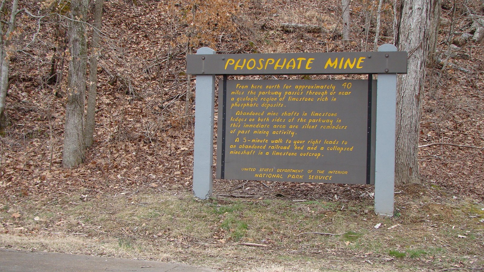 Wooden sign painted with yellow letters. Phosphate Mine is across the top