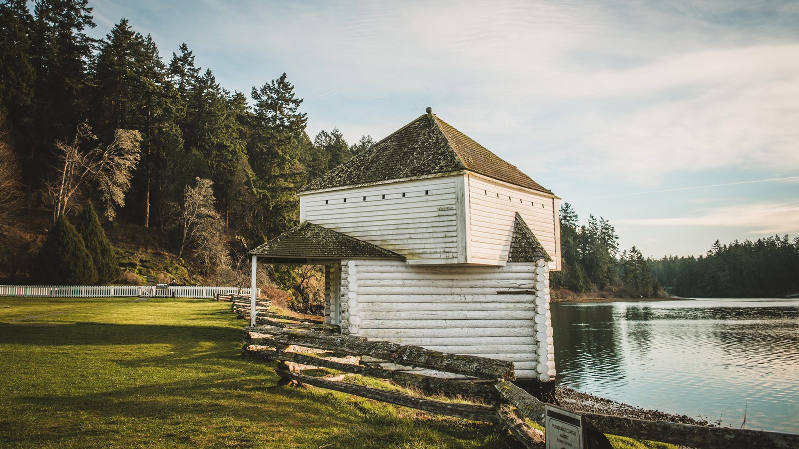 Color photograph of a wood framed two story structure by the water.