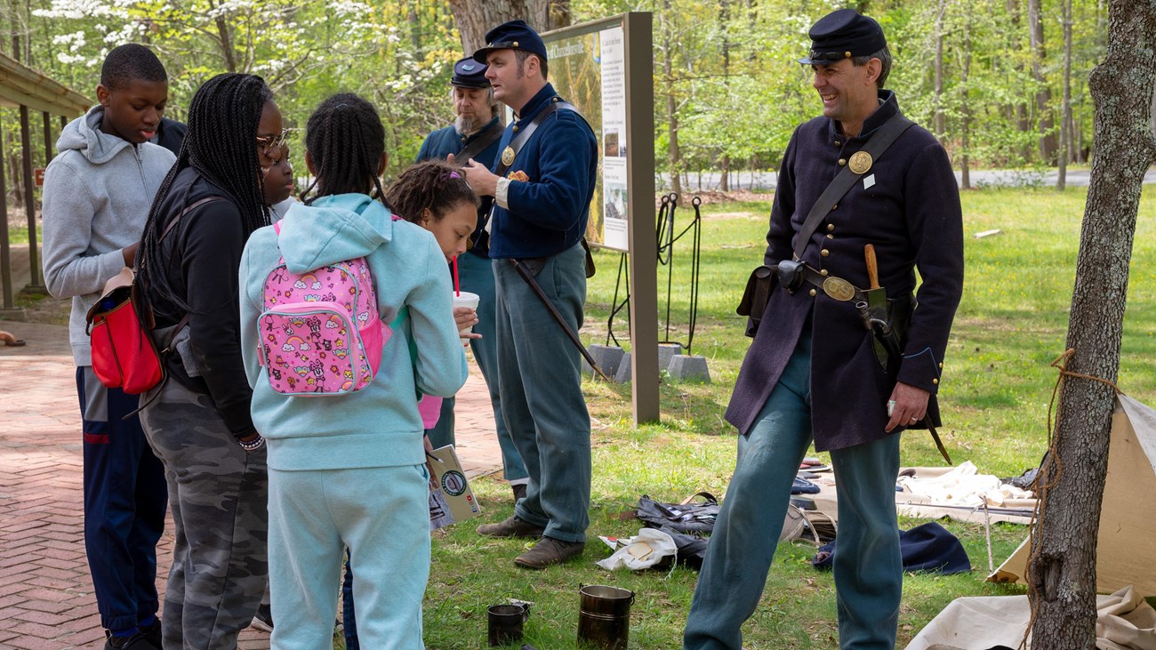 A family speaking to a living historian dresses as a Union Civil War soldier.