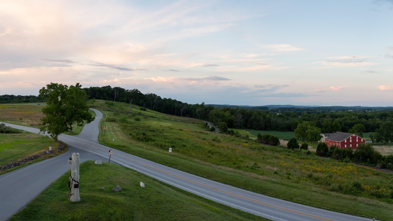 Panorama of street intersection across farm fields with scattered monuments,