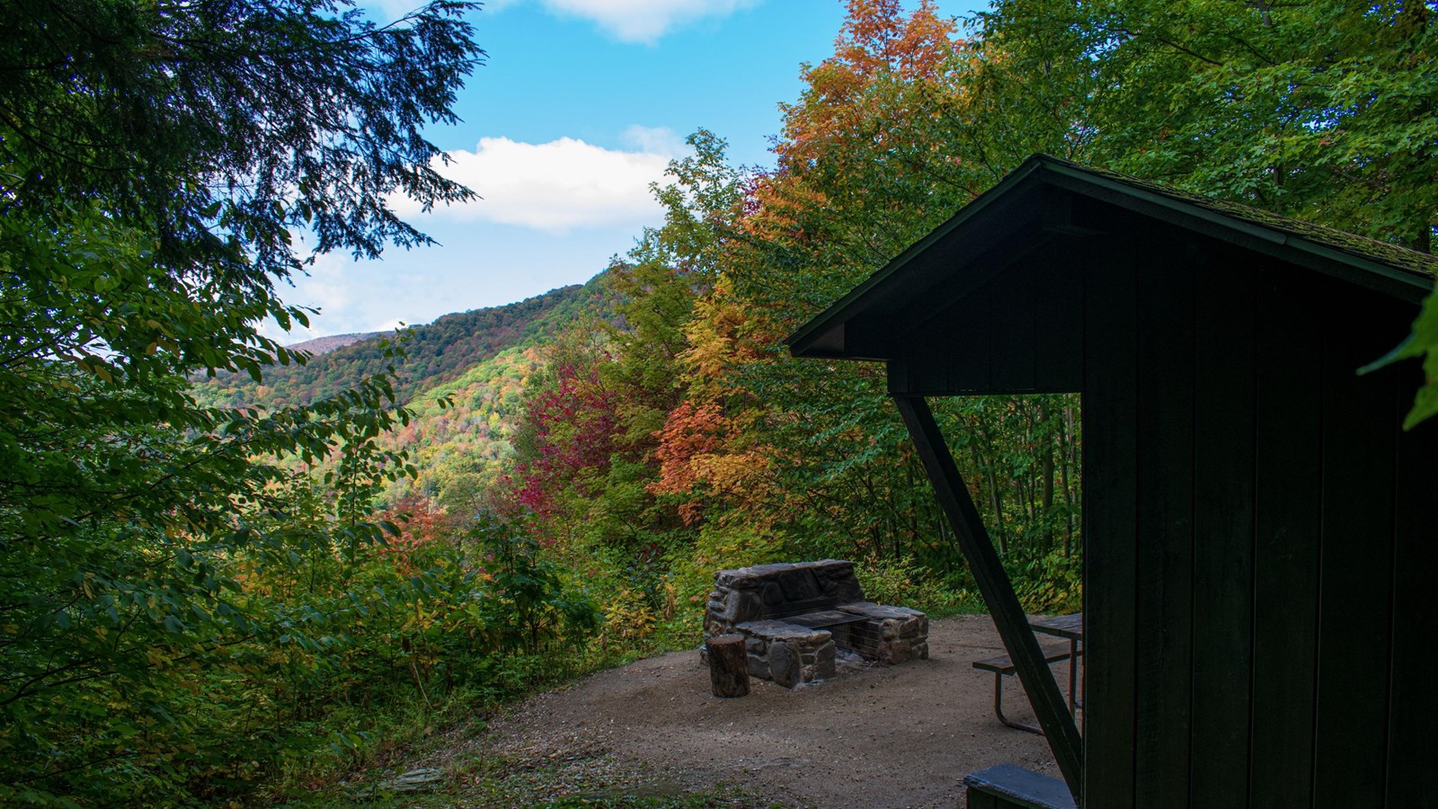 Image of a mountain overlook. There is a small, wooden outpost to the right of the image.