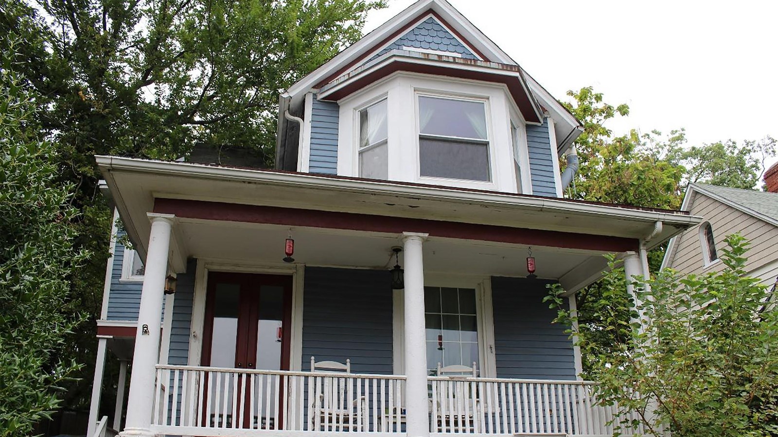 Domestic two story dwelling with a porch leading to the main entrance. The house sits atop a small