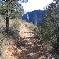 A trail cuts through a desert mountain landscape.