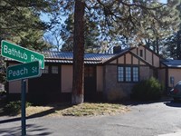 A car from the 1940s is parked in front of a house, on the left is green street sign.
