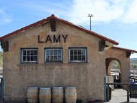 A cement building with a red tile roof. Above three windows text reads, "LAMY"