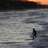 Surfer rides the waves at Portage Lakefront and Riverwalk at the Indiana Dunes National Park.