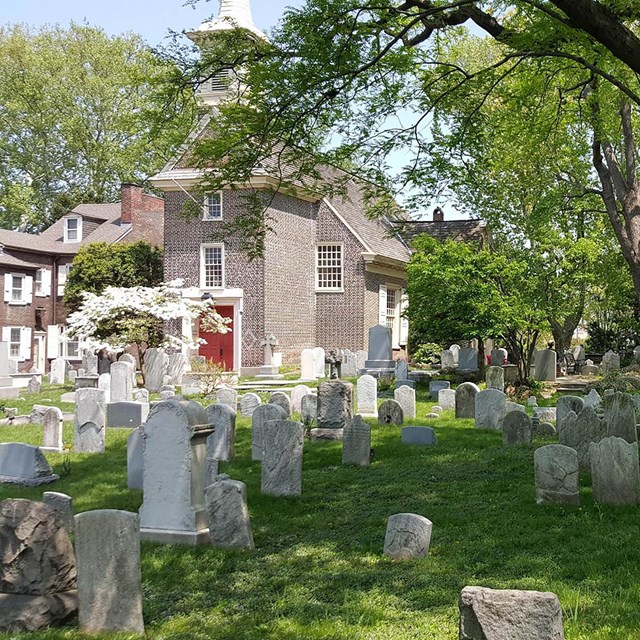 Color photo with brick church building in background, and cemetery in foreground.