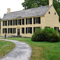 Looking down a path to a two story yellow house