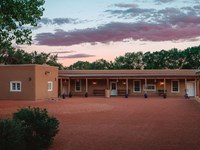 A pink-hued sunset sky, above a single story adobe building.