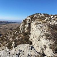 A desert mountain ends abruptly with a grey cliff
