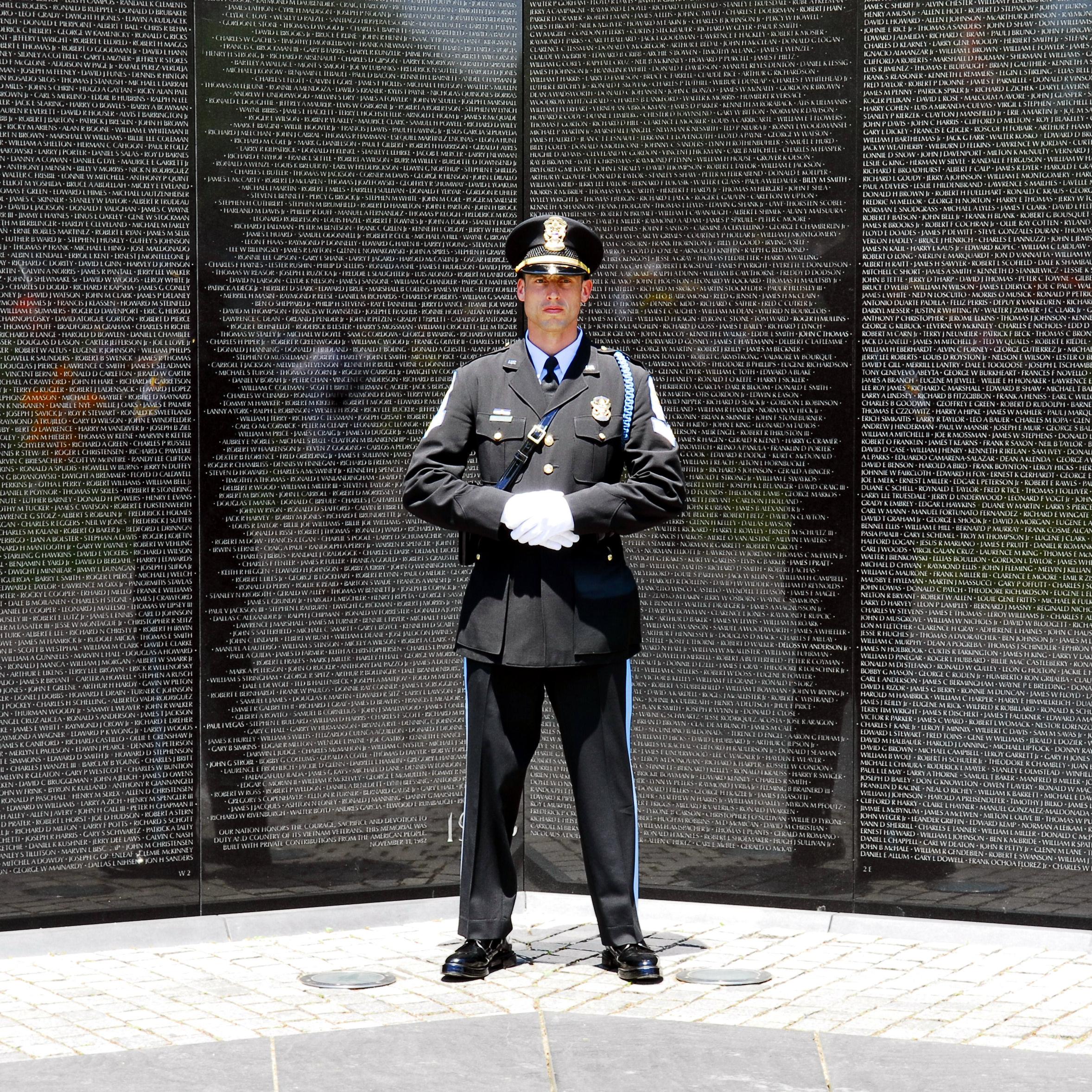 US Park Police Officer standing in front of the Vietnam Veterans Memorial.