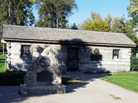 A historic one room log cabin in a park.