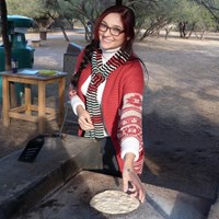 young woman flipping a flour tortilla on an open comal