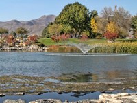 With mountains and fall foliage in the background, a fountain sprays water out of a small pond.