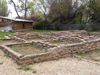 Short stone walls form the shapes of rooms on a grassy lawn.