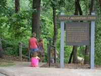 A family heading down step on a trail with a sign that says Little Mountain Trail
