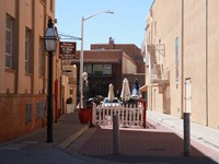 View down a narrow alley between two tall stucco office buildings.
