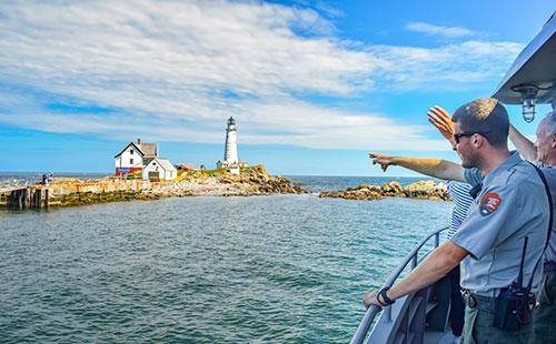 Ranger pointing at Boston Lighthouse from the water.