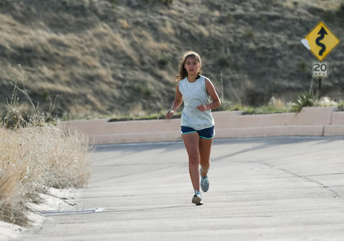 A woman jogs up a concrete-surfaced road.