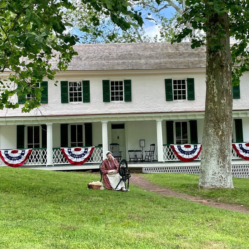 A spinner on the lawn in front of a white historic home with red, white and blue decorations