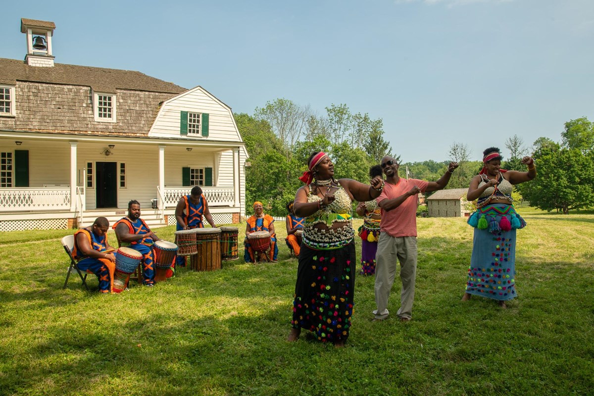 Performers in front of a farmhouse.