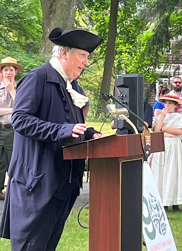 Man in replica 18th century speaking at a podium