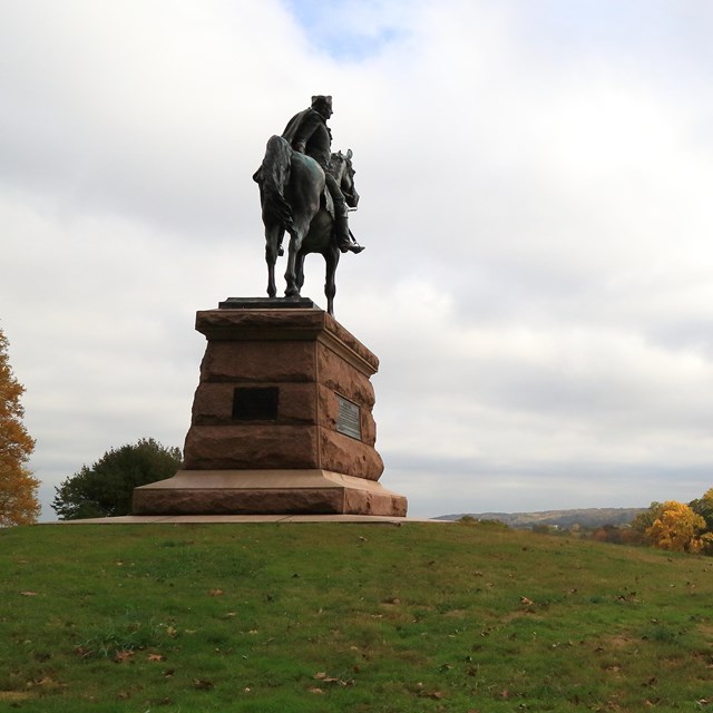 Bronze statue of a man on horseback overlooking a valley