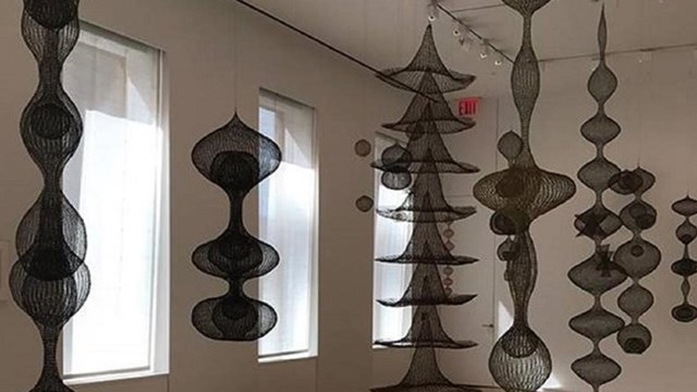 Photo of Ruth Asawa's wire sculptures, spiraled and hanging from the ceiling.